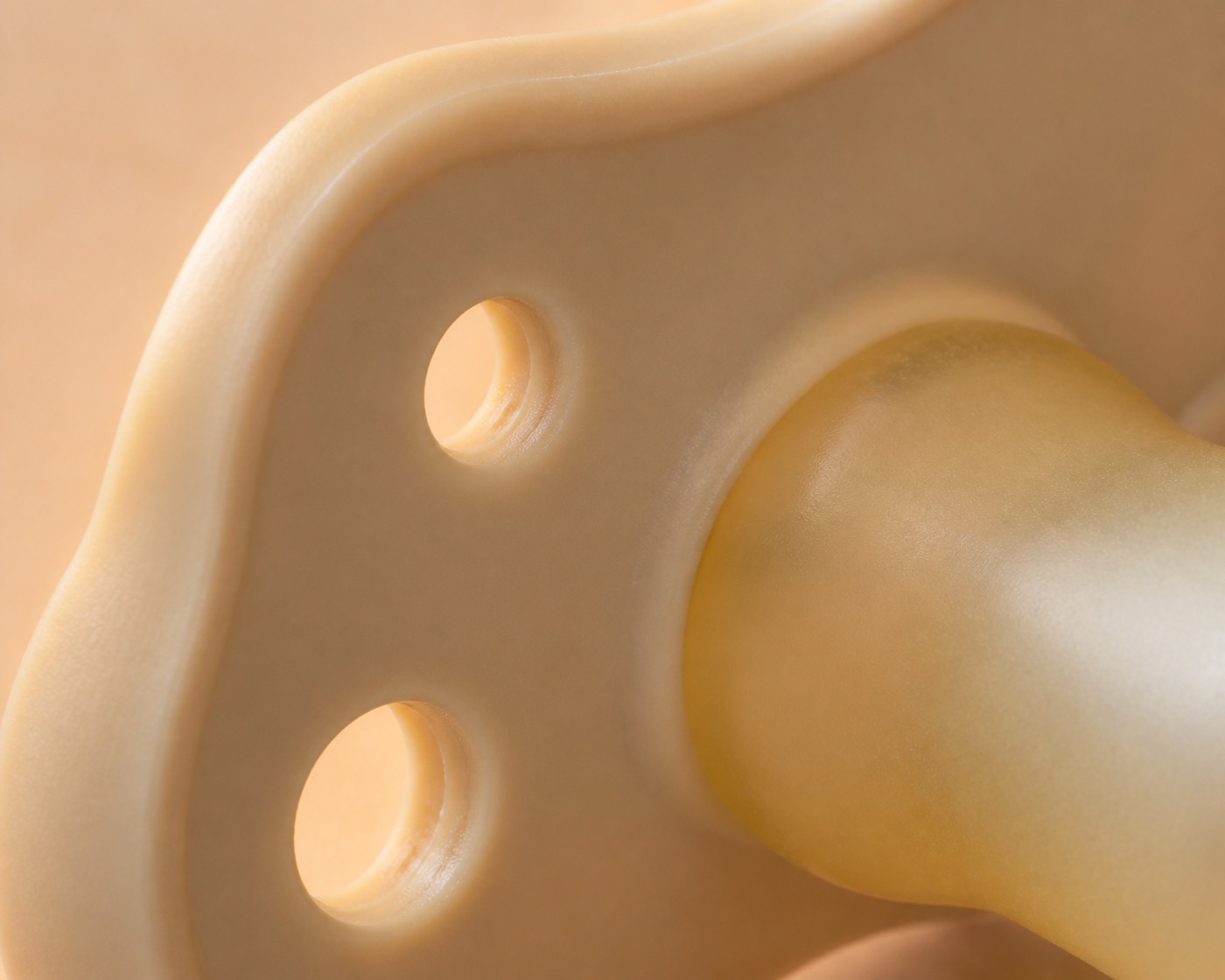 Close-up van een fopspeen met gebogen schildje op een zachte ondergrond